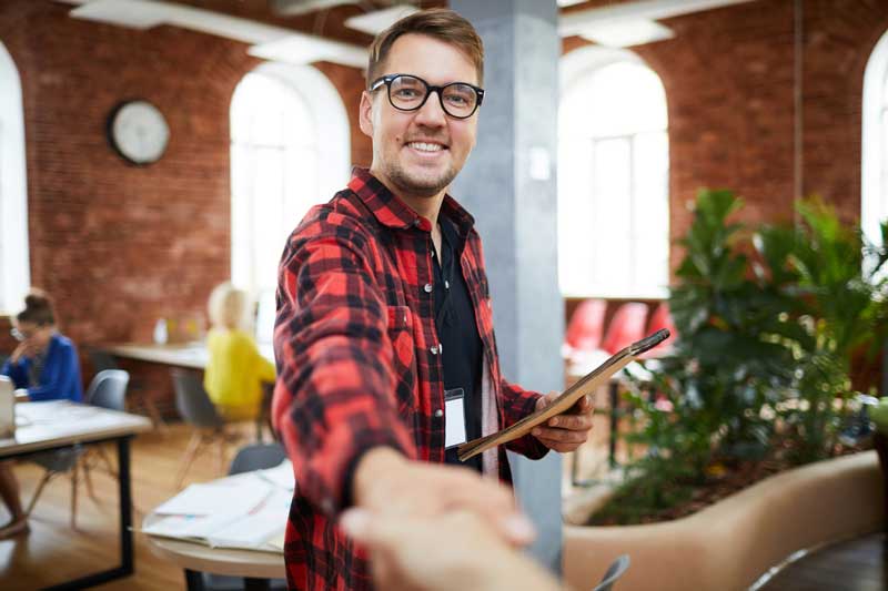 Connect with YesGig, man in flannel looking at the website viewer with hand outstretched ready to shake hands